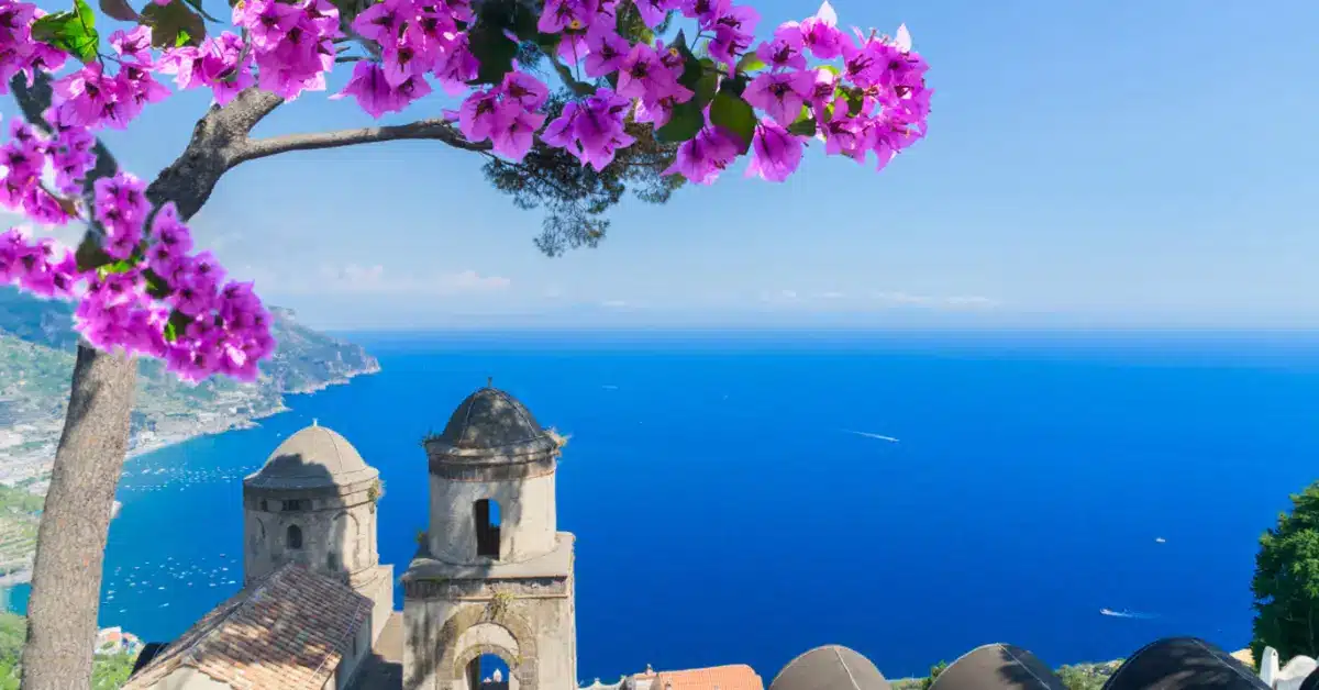 A stunning view of the Amalfi Coast from Ravello, framed by bougainvillea, showcasing the long-term benefits and property appreciation potential for investors in Italy.