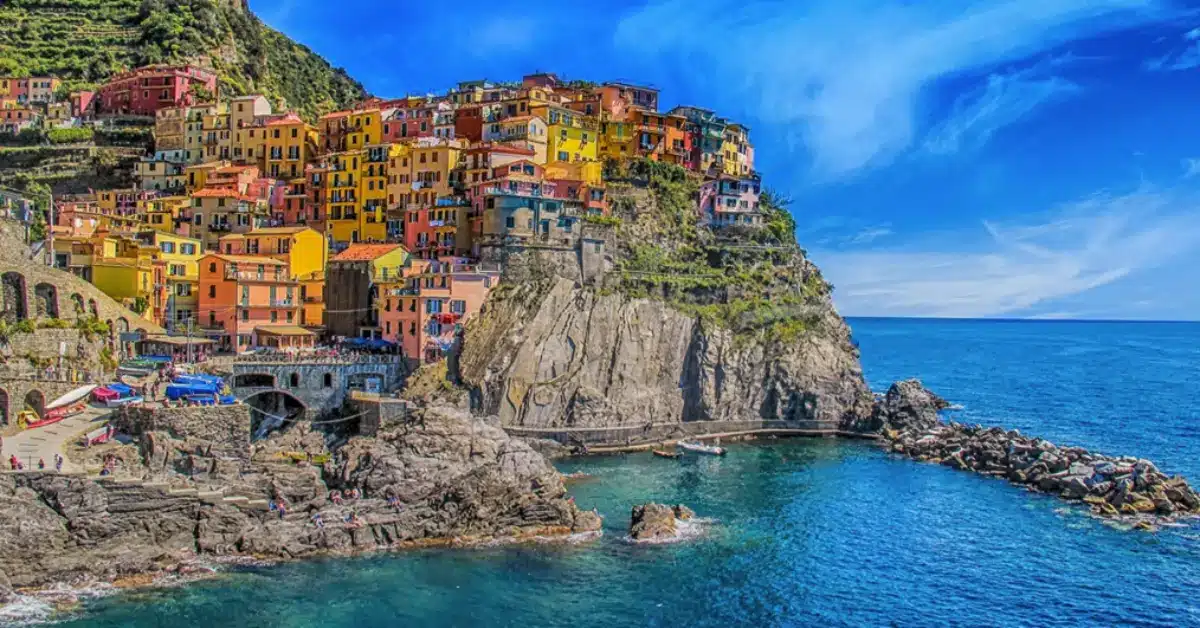 Colorful cliffside houses in Manarola, Cinque Terre, illustrating the desirable but complex property purchase process for foreigners in the Liguria region of Italy.