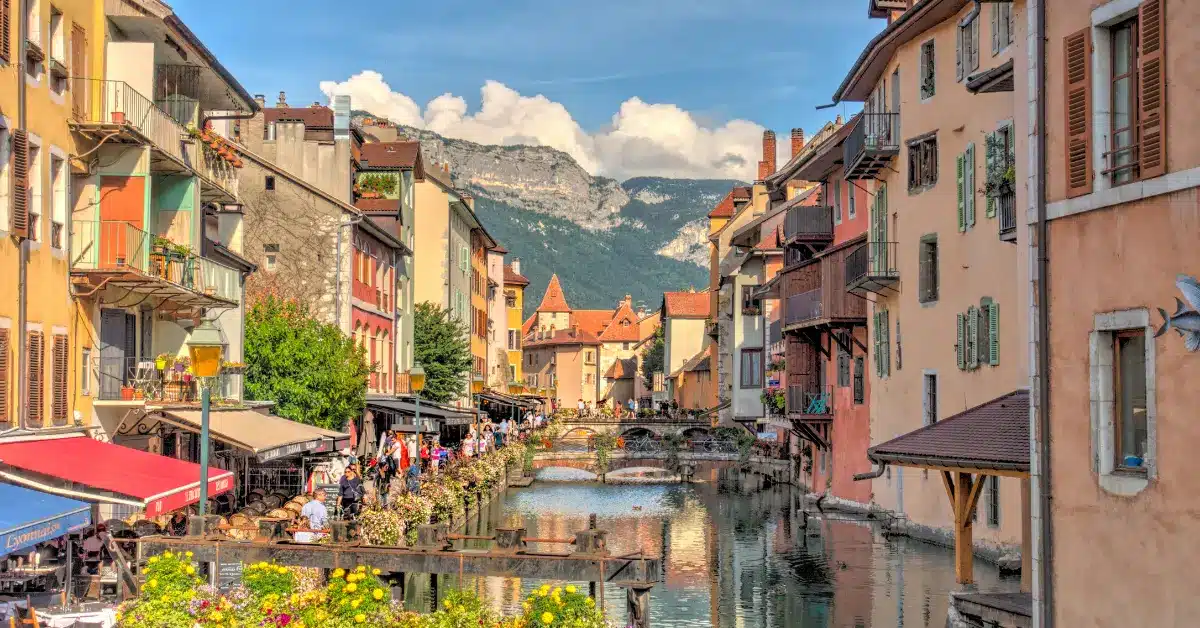A charming street in Annecy, an idyllic location when buying property in france, featuring a picturesque canal and historic alpine buildings.