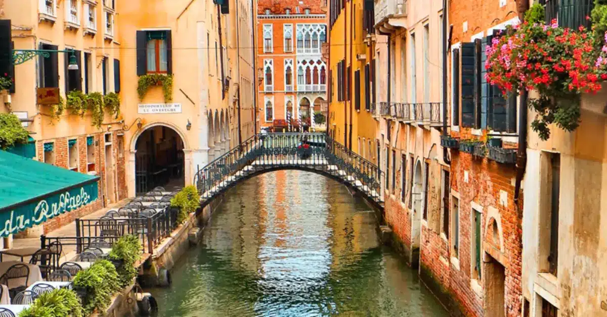 A picturesque bridge over a narrow canal in Venice, symbolizing the legal and regulatory steps involved for non-residents buying property in Italy.